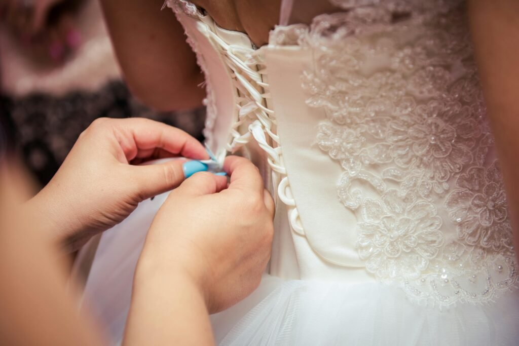 Detailed image of hands lacing a beautiful bridal gown, showcasing elegant wedding preparation.