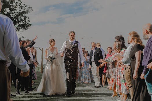 Bride and groom surrounded by guests celebrating with confetti outdoors.